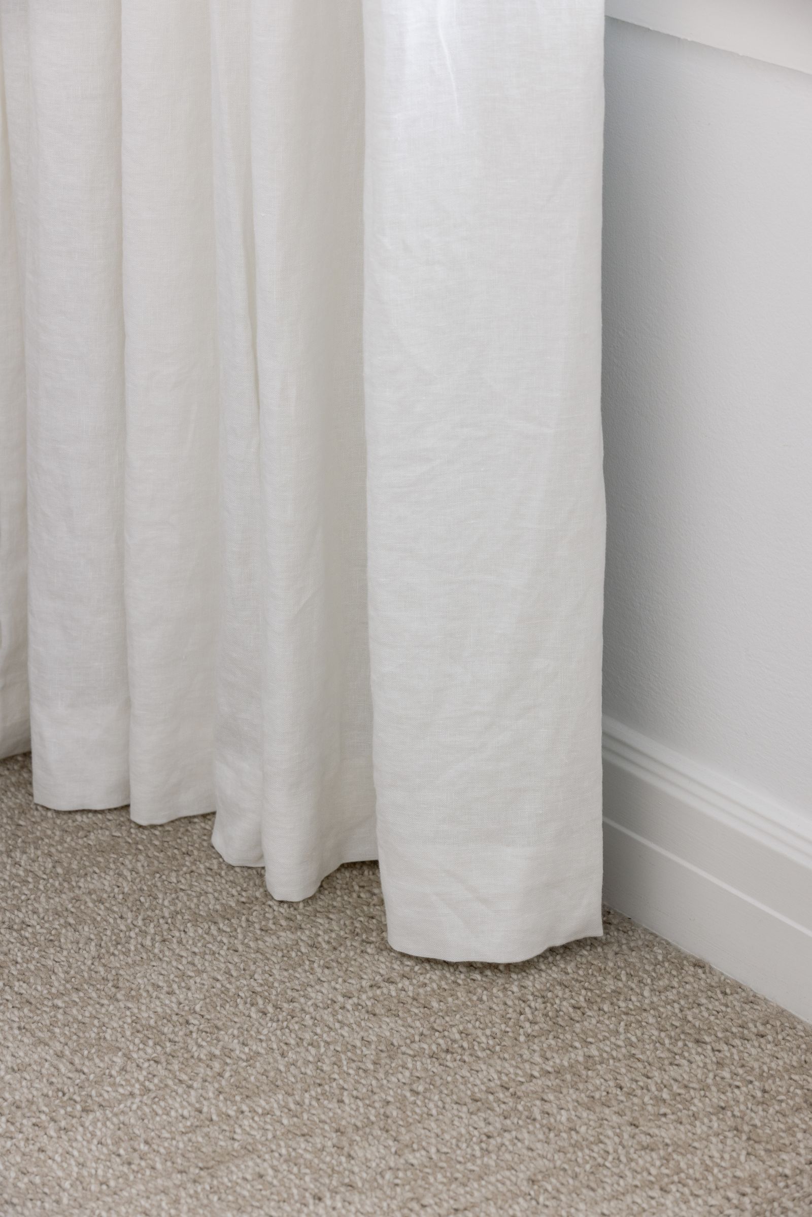 Soft cream curtains framing master bedroom windows
