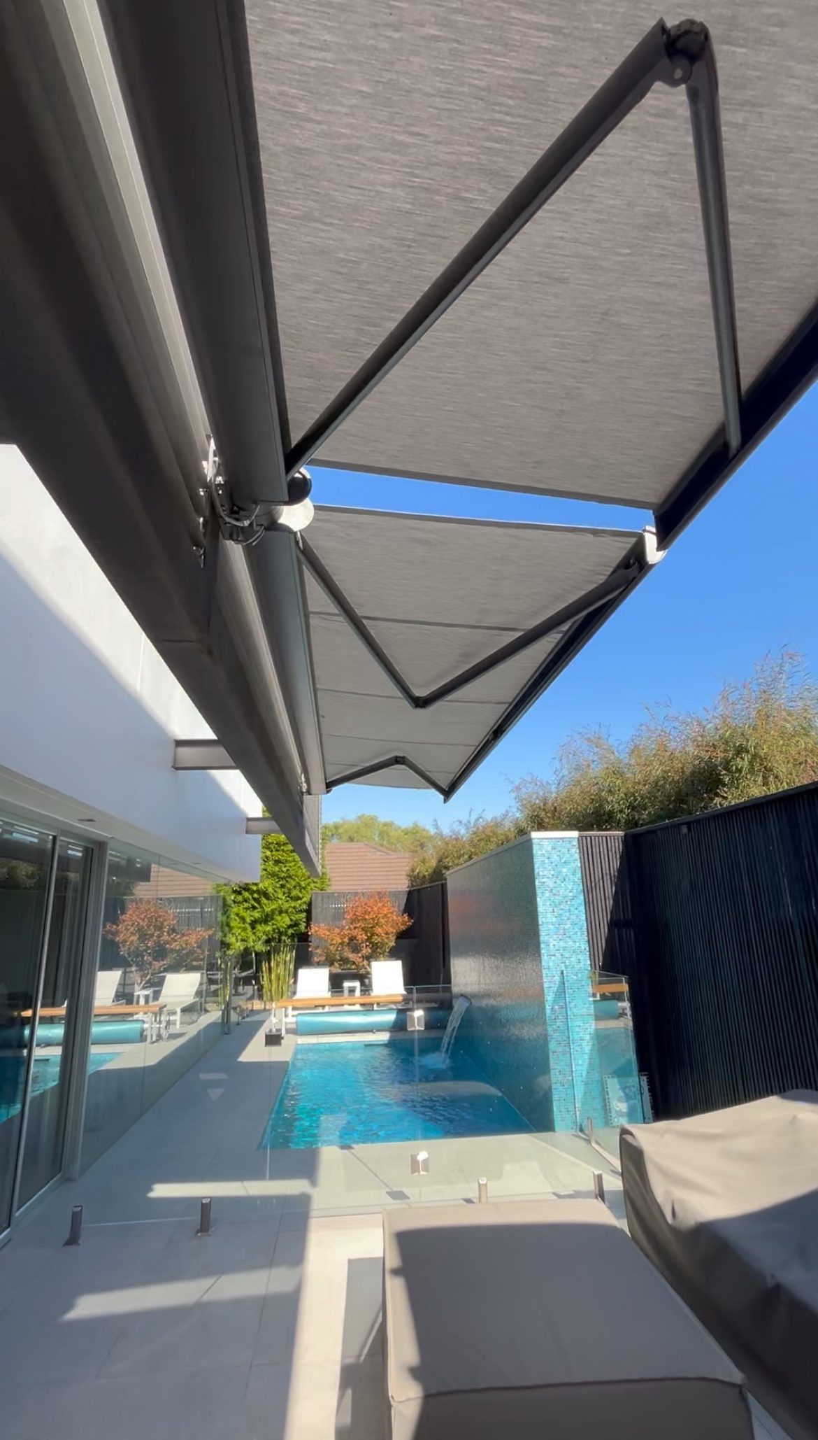 Motorised folding arm awning over a Melbourne poolside home